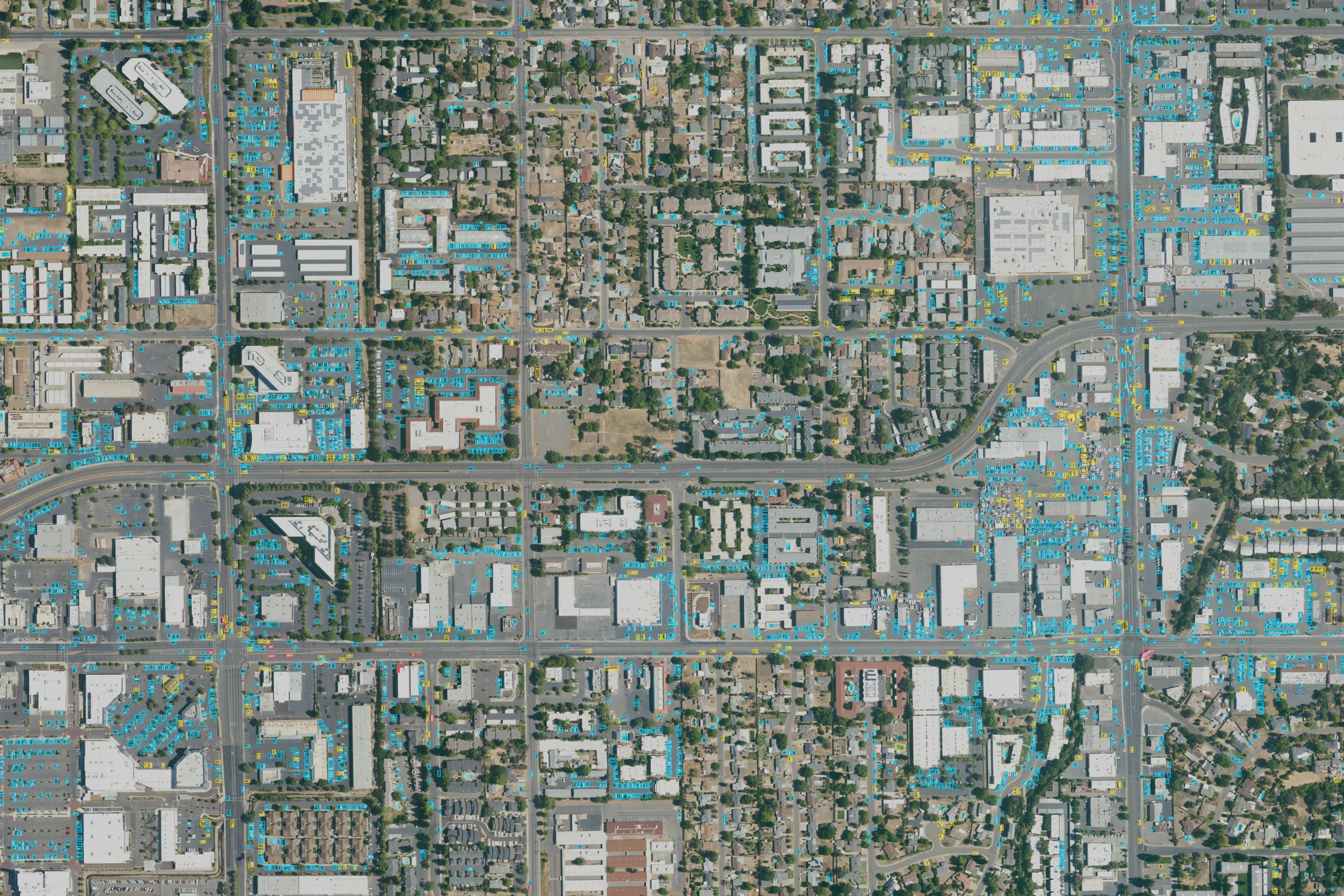 The same Sacramento suburb, with thousands of small outlined rectangles on the parked and moving vehicles in car parks, along roads and on driveways. Cyan outlines are vehicles the model classed as cars, yellow as trucks, and a few red as buses. Some outlines sit on rooftop equipment rather than vehicles.